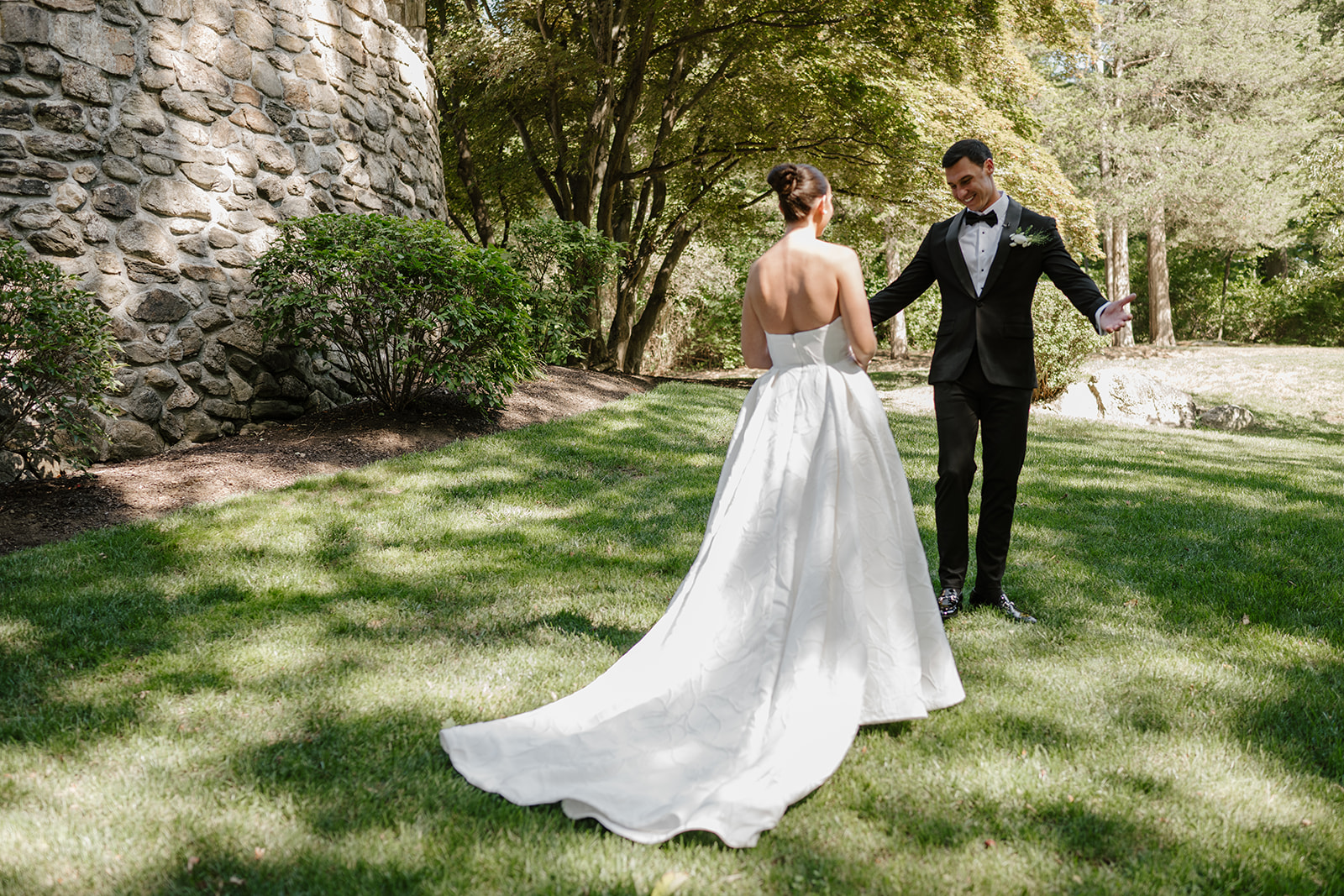 Groom smiling with open arms as he sees his bride for the first time on the lawn of Le Chateau.